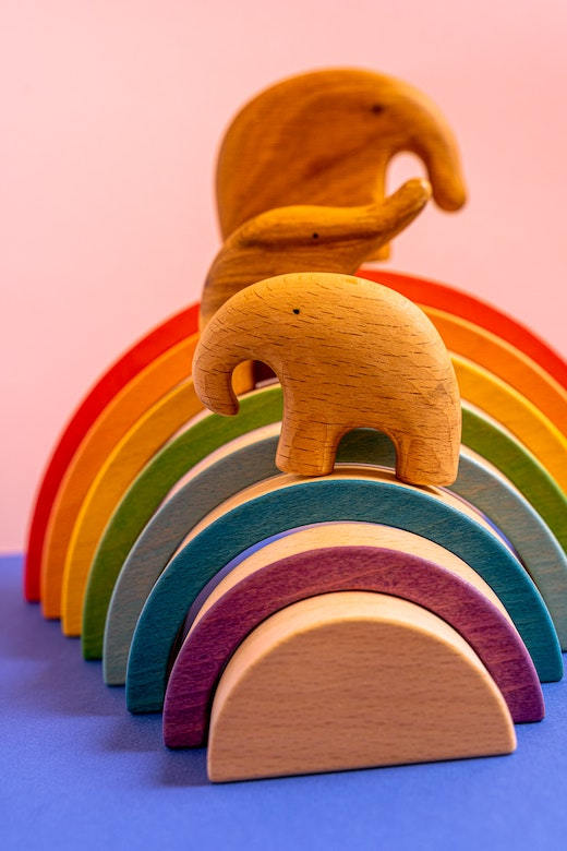 Kinderspielzeug aus Holz, das einen Regenbogen und eine Elefantenfamilie darstellt
